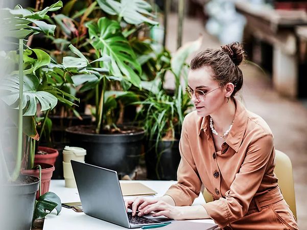 Frau sitzt am Arbeitsplatz und schaut sich Nachhaltigkeits-Produkte der Telekom an. 